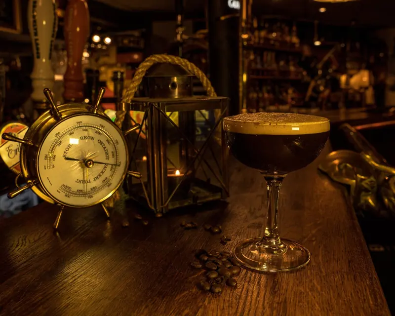 Espresso martini bredvid en barometer i mässing